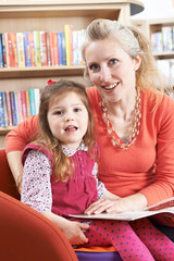 Fototapeta premium Mother And Daughter Reading Book In Library
