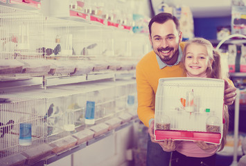 Father and daughter enjoying their purchase of canary bird in pet shop