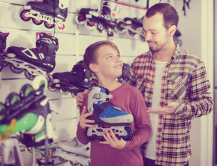Seller assisting boy in choosing roller-skates