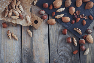 Variety of nuts: almonds, mountain almonds and hazelnuts on rustic wooden background.
