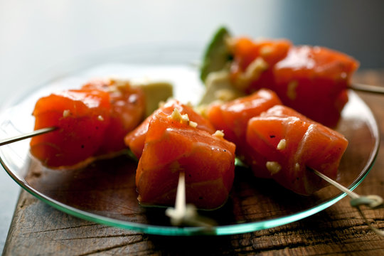 Marinated salmon on sticks, on glass plate, close-up