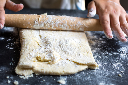 Person rolling pastry with rolling pin, close-up