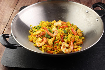 Udon stir-fry rice with shrimp and vegetables in wok pan on black burned stone background