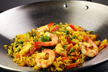 Udon stir-fry rice with shrimp and vegetables in wok pan on black burned stone background
