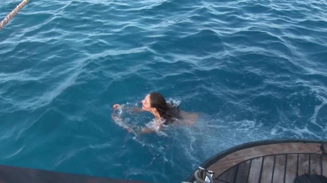 Free diver model mermaid dives from ship near water in Red Sea. Filming a movie. Young girl smiling at camera.