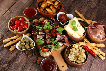 Italian antipasti wine snacks set. Cheese variety, Mediterranean olives, pickles, Prosciutto di Parma, tomatoes, artichokes and wine in glasses