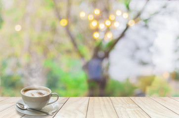 Coffee cup with smoke and spoon on white wooden terrace over blur light bokeh on tree branch background