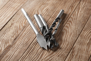 set of different drill bits on wooden background