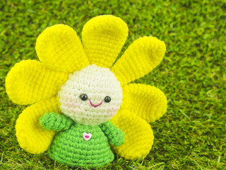 Happy baby flower, handmade crochet doll on green grass background