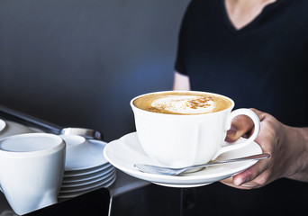 Coffee cup is serving by barista in the partial dark room shop