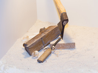 Old ax, plane, chisel and wood shavings on a light background