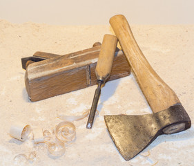 Old ax, plane, chisel and wood shavings on a light background