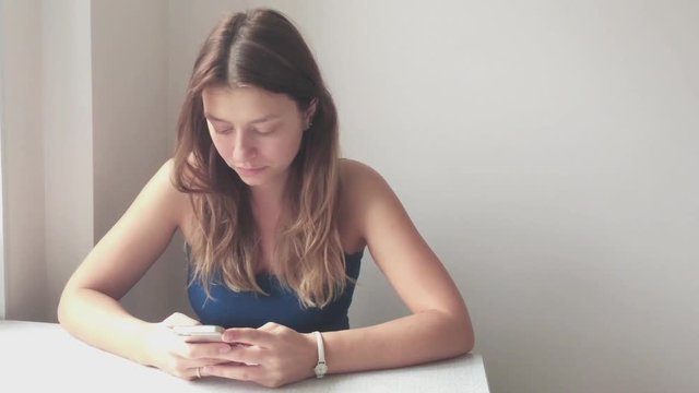 Girl with blond hair looking at the phone. Close-up