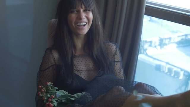 Smiling brunette female sitting near window