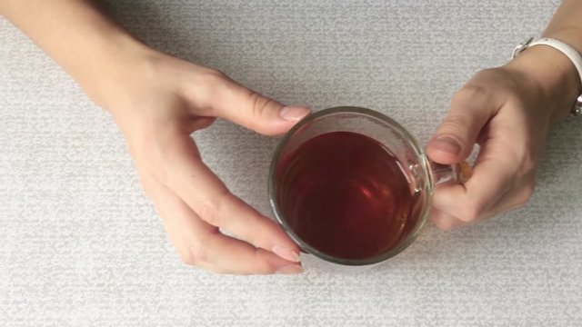 Female hands close up holding cup of hot tea