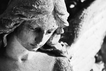 Vintage image of a sad angel on a cemetery against the background of leaves