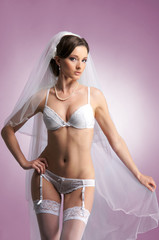 Young sexy bride in erotic lingerie over pink background.