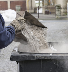 man throwing ashes in a trash bin.