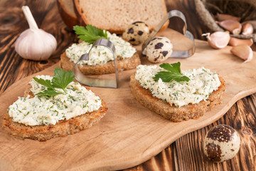 a sandwich in the shape of a heart with egg, cheese, dill, garlic on a wooden table