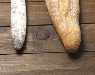 Bread fuet on wooden table. Spanish sausage. Horizontal shoot. - obrazy, fototapety, plakaty