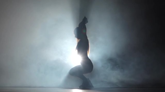 Sexy woman in dark studio booty dance in silhouette. Slow