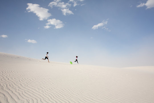Young couple running on sand dune 