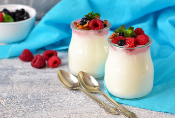 Vanilla yogurt with berries on a concrete background.