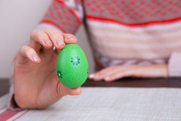 Fototapeta na wymiar Green colored easter egg in female hands