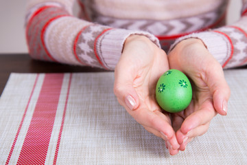 Green colored easter egg in female hands