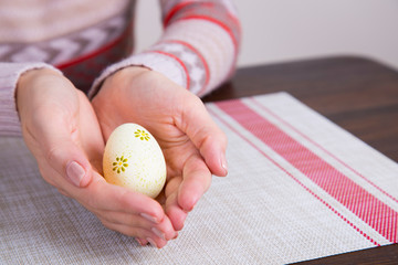 Fototapeta na wymiar Yellow colored easter egg in female hands