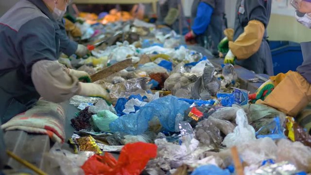 Waste recycling plant. Workers sorting garbage for recycling. 4K.