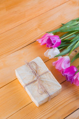 Obraz na płótnie Canvas Bouquet of tender pink tulips with gift box on light wooden background