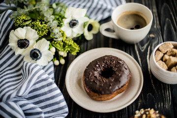 Cup of coffe and a chocolate donuts on black wood
