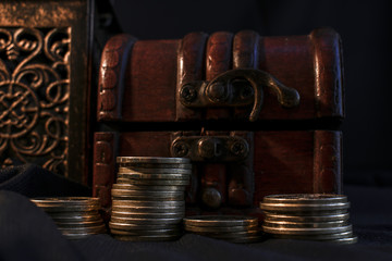 Treasure chest, pillar of coins and candle lamp in dark environment 