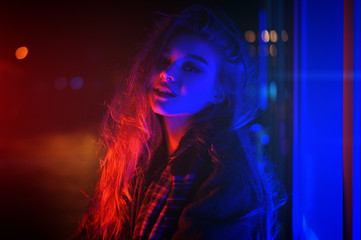 Obraz na płótnie Canvas Sexy young woman posing over night city dramatic neon background