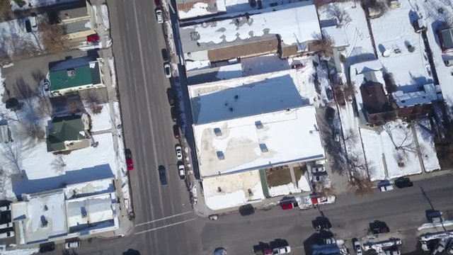 Aerial drone Surveillance over rural city main street. Aerial point of view. First winter storm and blizzard white snow. Rural farm community. Hazard to driving. Travel along Main Street.