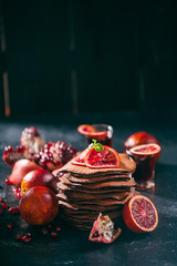 Chocolate Pancake with citrus and pomegranate on a wooden background in rustic style