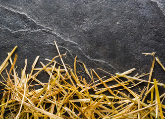 A bunch of yellow straw on the black background of an empty slab of slate.