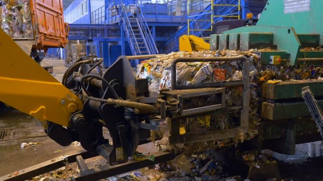 Machine loading blocks of waste at a recycling plant. 4K.