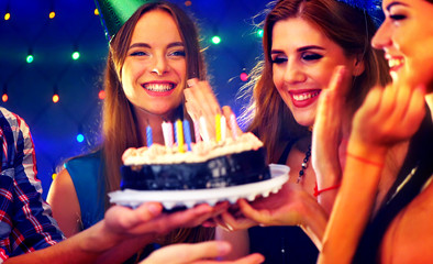 Happy friends birthday party with candle celebration cakes. People looking at burning candles and...
