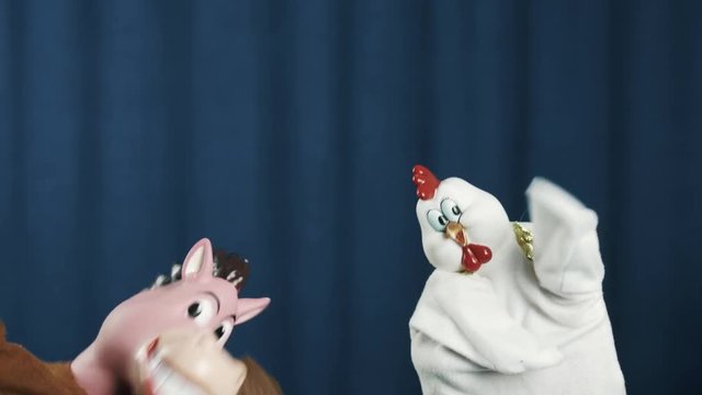Cute white chicken and smiling horse hand puppet toys dancing and waving on scene with blue crease curtains background