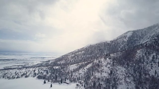 Aerial fly towards mountain valley cabin winter snow. Winter snow on landscape of central Utah. Cold season weather. Nature and environment. Beautiful natural environment. Drone flight.