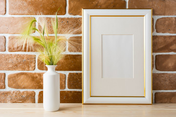Gold decorated frame mockup with ornamental grass exposed brick wall