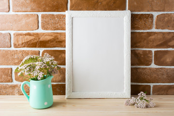 White frame mockup with creamy pink flowers near exposed bricks