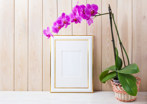 Gold decorated frame mockup with purple orchid in wicker basket
