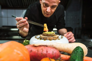 Chef is concentrated on preparing modern molecular dish with pincers