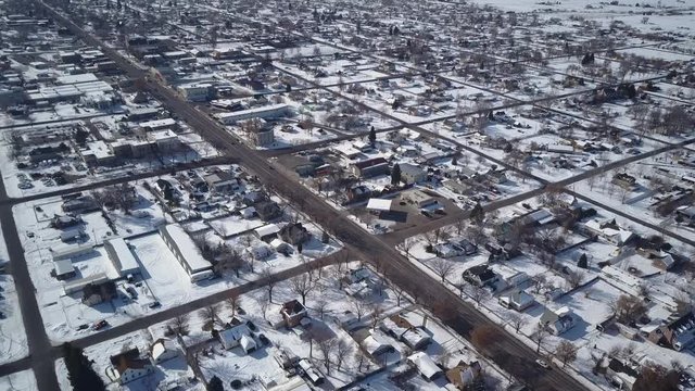 Aerial Ephraim Utah rural city homes and traffic. Aerial point of view. Winter storm and blizzard white snow. Rural farm community. Homes, barns and buildings covered with white.