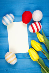 Fresh tulips and Easter eggs wrapped woolen string, Easter decoration, copy space for text on sheet of paper