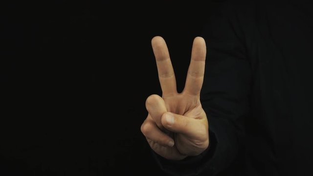 Caucasian male hand in long sleeve jacket make variety of positive finger gestures on black background, close up isolated. Okay, peace and horn signs, thumb up