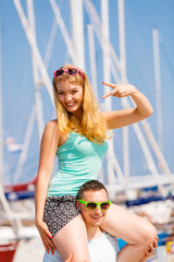 Man giving girlfriend piggyback ride on marina